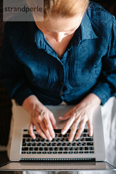 Draufsicht auf eine reife Frau  die einen Laptop benutzt und zu Hause arbeitet