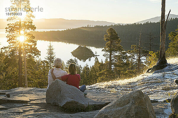 Ein Mann und eine Frau entspannen sich bei Sonnenaufgang auf dem Gipfel der Eagle Falls.