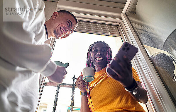 Glückliches multiethnisches Paar beim Kaffee trinken zu Hause