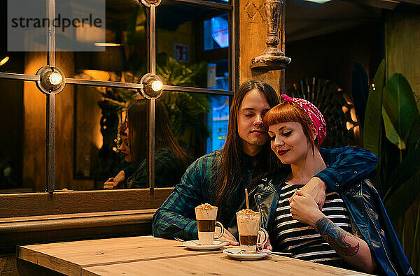 Hübsches Pin-up-Paar  das mit geschlossenen Augen in einem Cafe sitzt