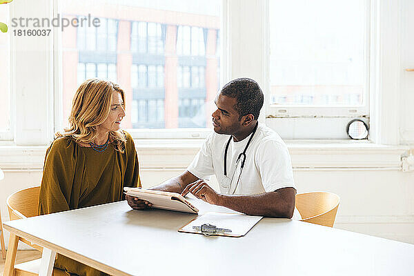 Arzt diskutiert mit Patientin über iPad-Aufzeichnung in der Klinik