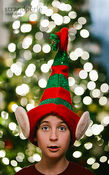 Preteen Junge in Weihnachten Elf Hut mit Weihnachtsbaum Licht Bokeh