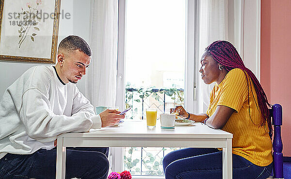 Glückliches multiethnisches Paar beim Frühstück zu Hause