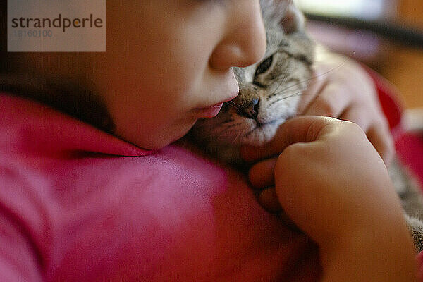 Nahaufnahme eines kleinen Kindes  das ein kleines Kätzchen küsst und streichelt
