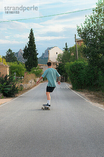 Junger Mann fährt auf einem Skateboard auf einer Straße