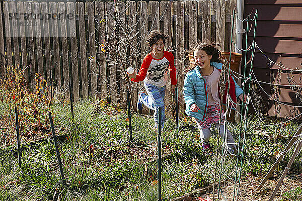 Zwei Kinder spielen Verfolgungsjagd durch den Garten im Frühling