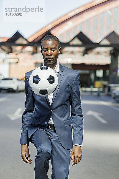 Businessman showing skills with soccer ball on sunny day
