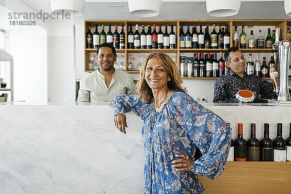 Glückliche Geschäftsfrau mit Barkeepern  die an der Bartheke im Restaurant stehen