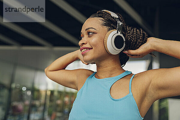 Lächelnde Frau  die über kabellose Kopfhörer Musik hört