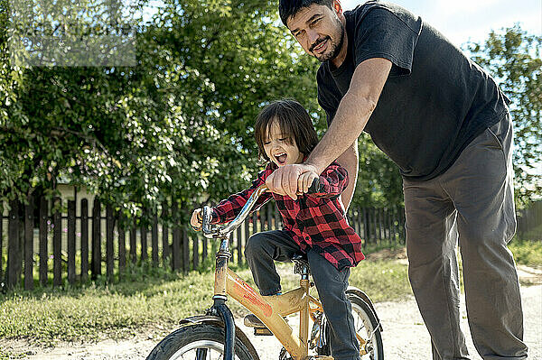 Mann schiebt Sohn auf Fahrrad