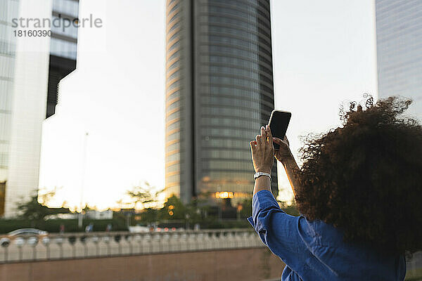 Frau fotografiert modernes Gebäude per Smartphone