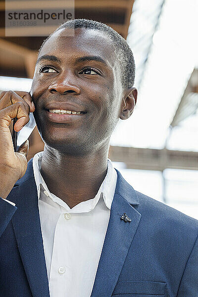 Happy young businessman talking on mobile phone
