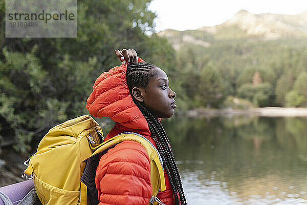 Junge Frau mit Rucksack am See im Urlaub