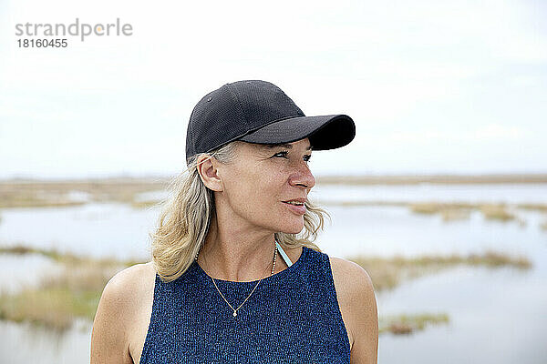 Senior woman wearing cap in front of lagoon