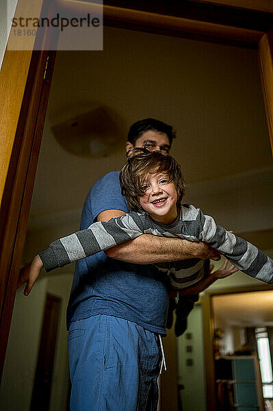 Playful man lifting son at home