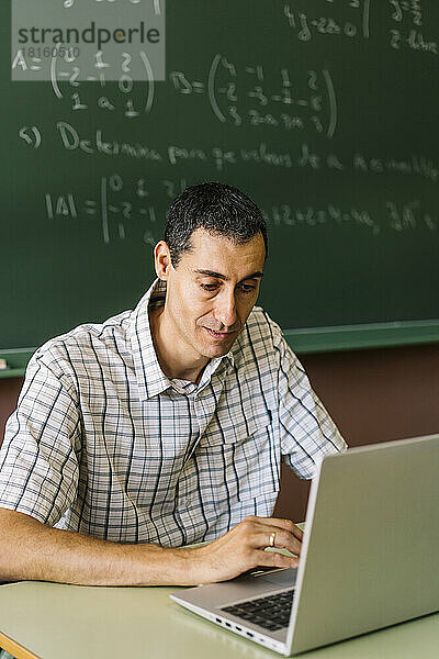 Mathematiklehrer benutzt Laptop im Klassenzimmer