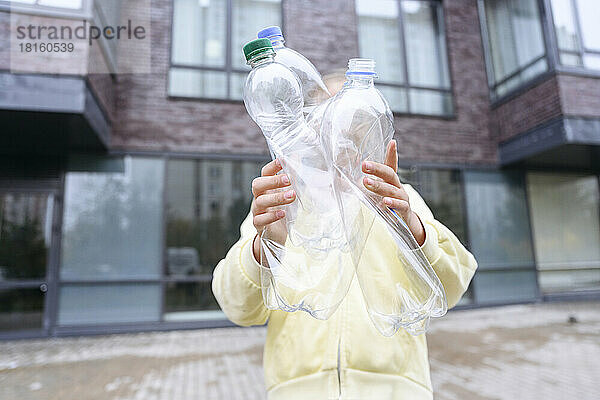 Mädchen hält leere Plastikflaschen auf Fußweg