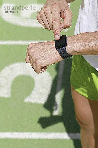 Sportler überprüft die Zeit auf einer Smartwatch an der Sportstrecke