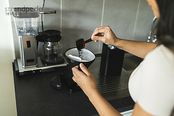 Frau bereitet zu Hause in der Küche Kaffee zu