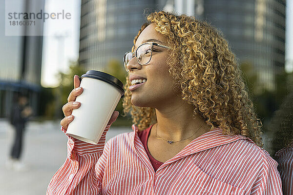 Lächelnde Frau mit lockigem Haar  die Kaffee trinkt