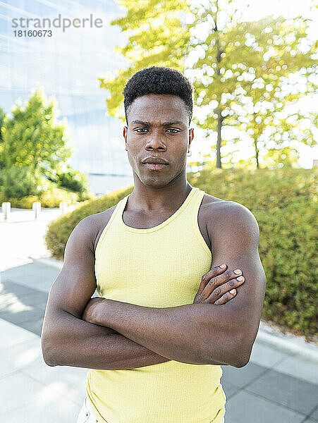 Confident young man wearing yellow vest standing with arms crossed