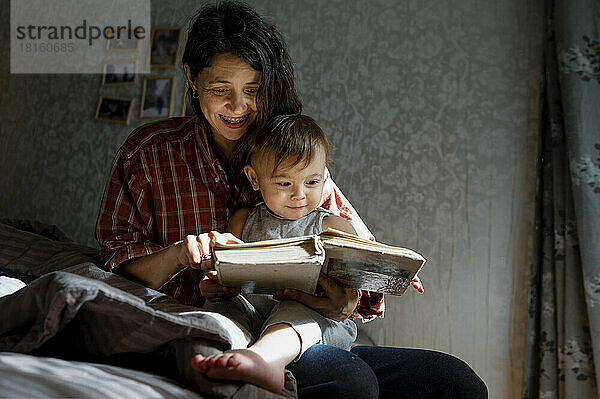 Glückliche Frau mit kleinem Jungen  der zu Hause ein Buch liest