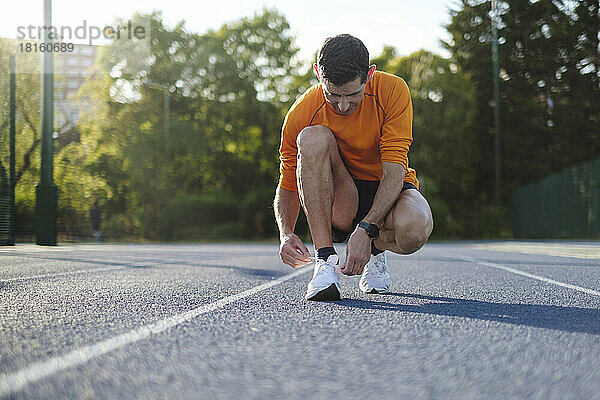 Sportler bindet Schnürsenkel auf der Strecke
