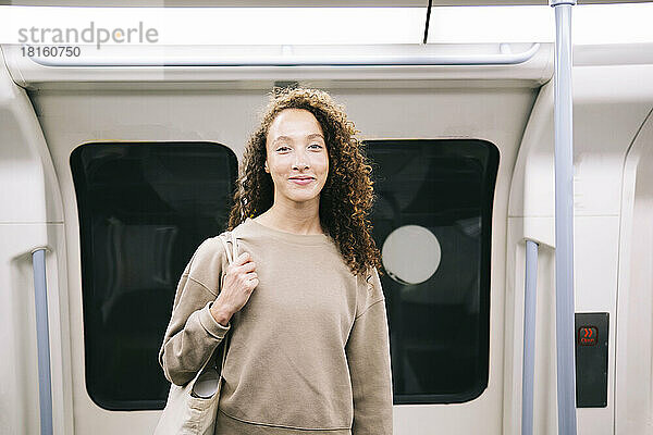 Lächelnde junge Frau  die in der U-Bahn unterwegs ist