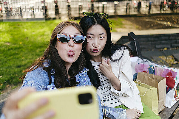 Lesbian friends making facial expressions taking selfie through smart phone