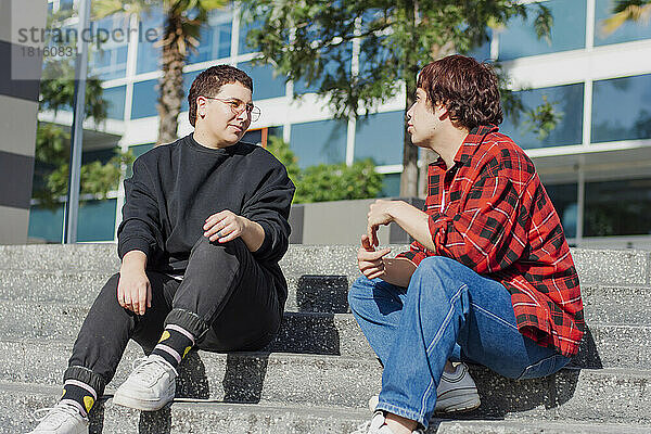 Non-binary couple sitting together on staircase in front of building
