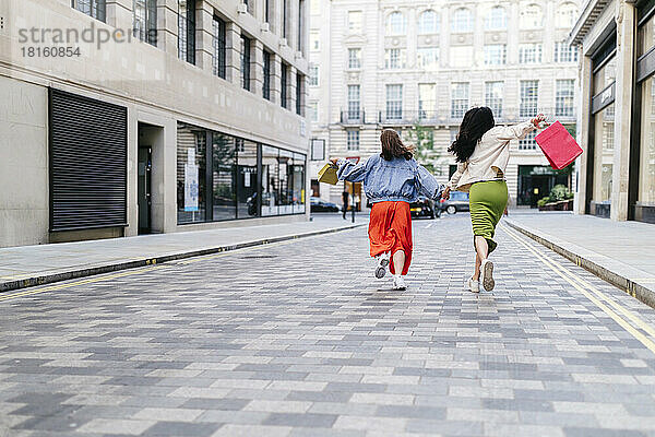 Sorglose lesbische Freundinnen mit Einkaufstüten laufen auf Fußweg