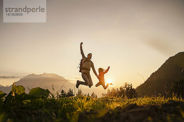 Glücklicher Mann mit Tochter  der auf den Berg springt