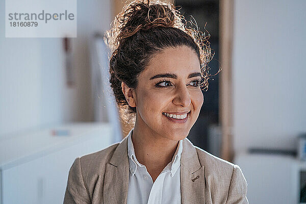 Lächelnde Geschäftsfrau mit Haarknoten im Büro