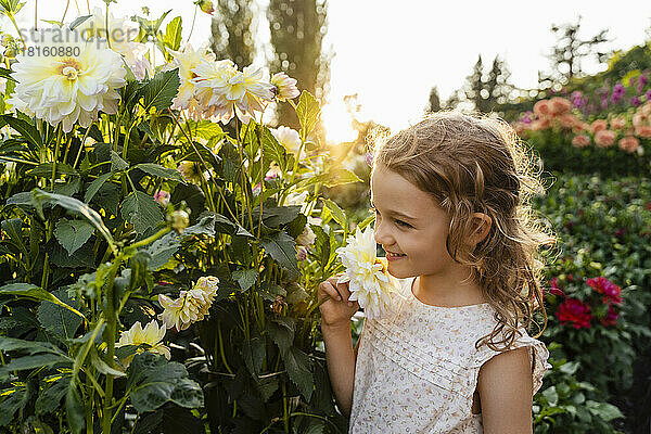 Kleines Mädchen riecht Blumen im Garten