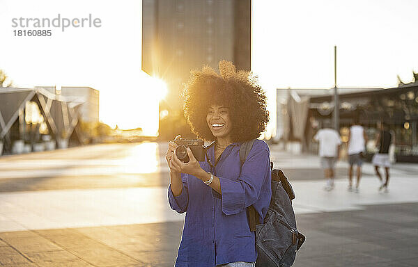 Glückliche Frau mit Afro-Frisur  die mit der Kamera fotografiert