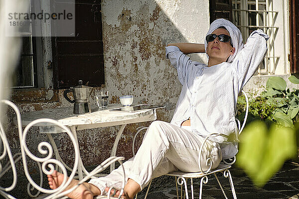 Frau mit Handtuch und Sonnenbrille entspannt auf der Terrasse