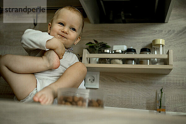 Niedliches kleines Mädchen  das zu Hause auf der Küchentheke sitzt