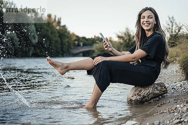 Fröhliche Frau spritzt Wasser mit dem Bein