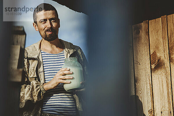 Reifer Mann mit einem Glas frischer Milch an einem sonnigen Tag