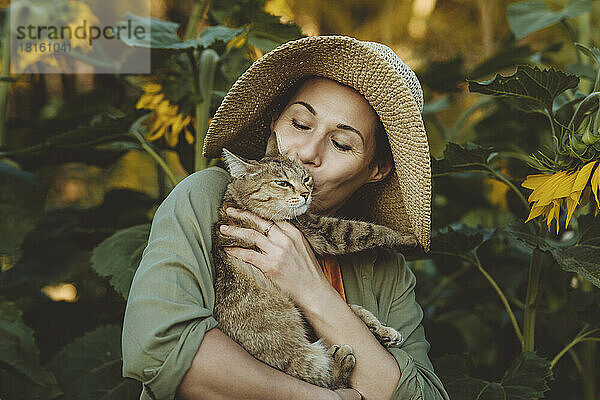 Reife Frau küsst getigerte Katze im Garten
