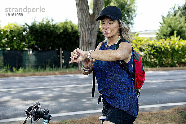 Ältere Frau auf dem Fahrrad überprüft die Uhrzeit mit einer Smartwatch