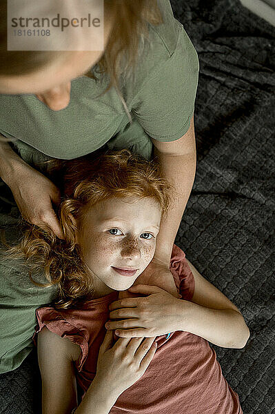 Daughter lying on mother's lap at home
