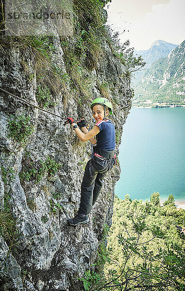 Lächelndes Mädchen klettert auf den Berg in der Nähe des Idrosees