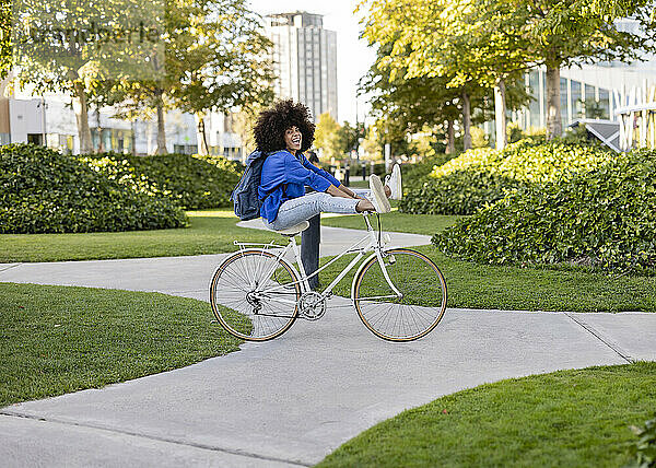 Fröhliche Frau sitzt auf dem Fahrrad im Park