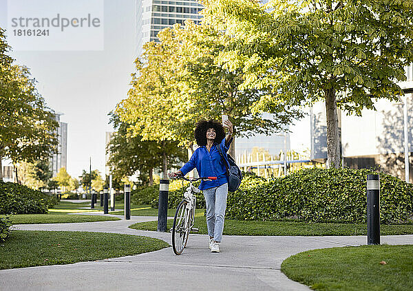 Glückliche Frau mit dem Fahrrad  die im Park ein Selfie mit dem Handy macht