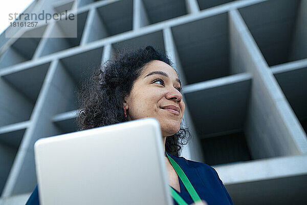 Lächelnde Geschäftsfrau mit Tablet-PC vor dem Gebäude