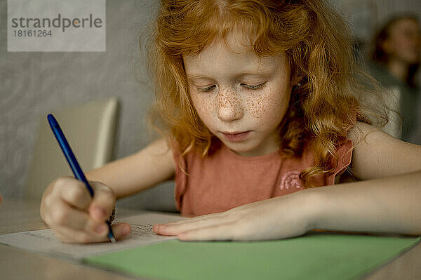 Rothaariges Mädchen zeichnet zu Hause mit Farbstift