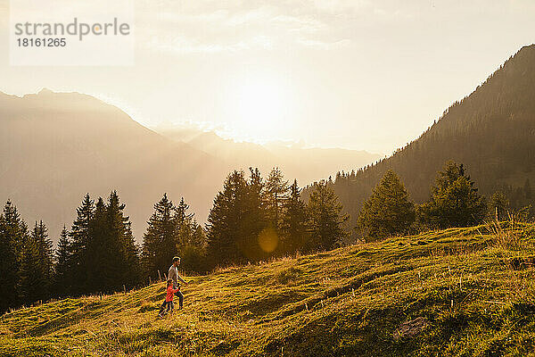 Mann mit Tochter wandert bei Sonnenuntergang auf dem Berg