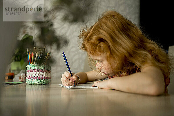 Mädchen zeichnet mit Farbstift am Tisch