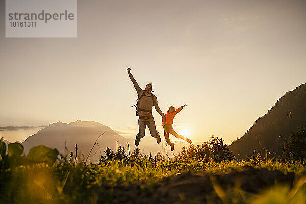 Glücklicher Mann mit Tochter  der auf den Berg springt